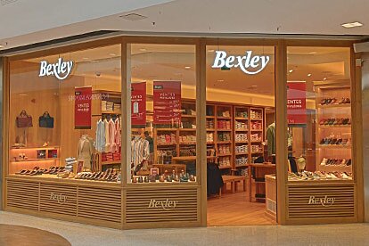 Façade de la boutique Bexley avec vitrines illuminées, chaussures et vêtements exposés.