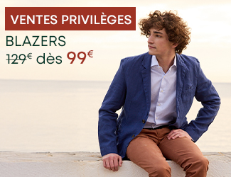 Homme en blazer bleu et chemise blanche au bord de la mer