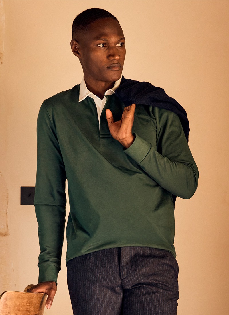Homme portant un polo manches longues vert foncé, pull marine sur l'épaule