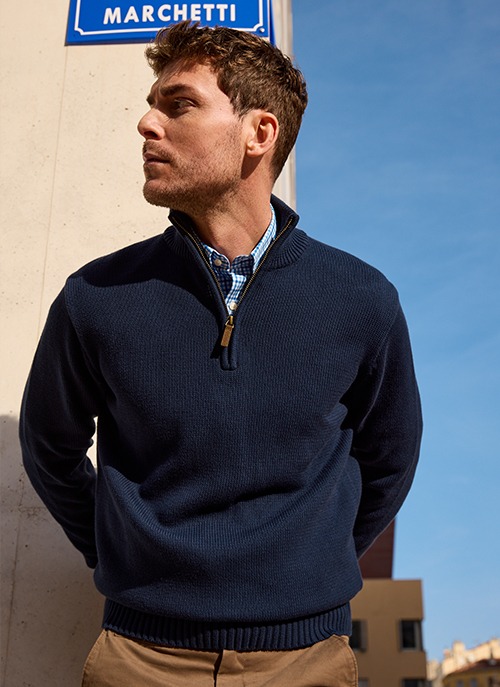 Homme portant un pull col zippé bleu marine dans un style casual chic.