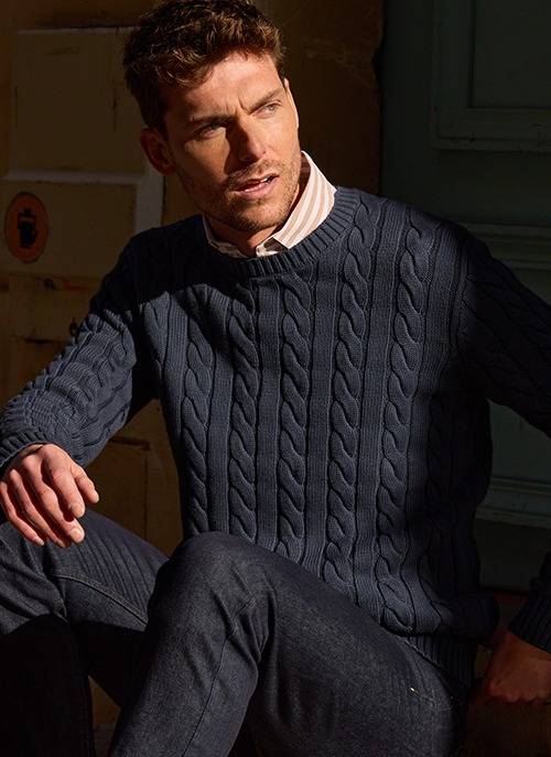 Homme portant un pull col zippé bleu marine dans un style casual chic.