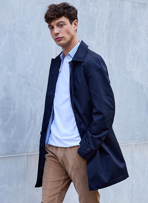 Homme portant un trench bleu marine léger, style urbain moderne.
